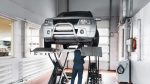 Mechanic inspect suspension system of lifted car